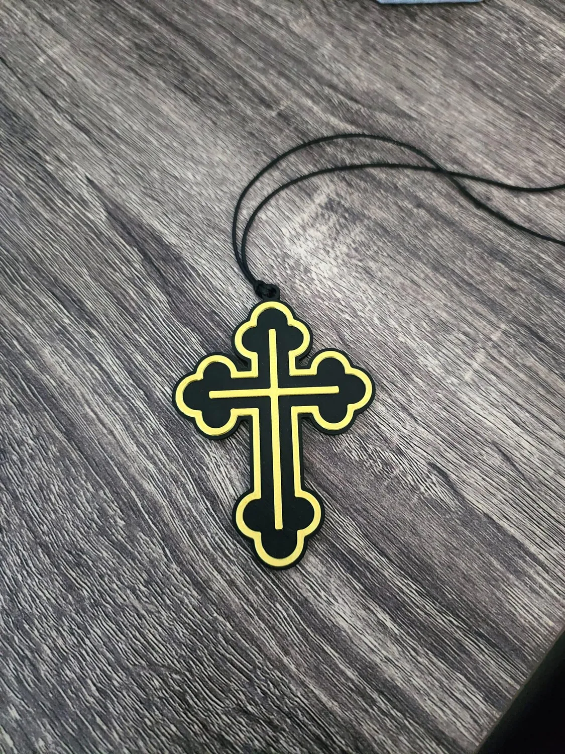 Black and gold budded Orthodox cross hanging from a cord