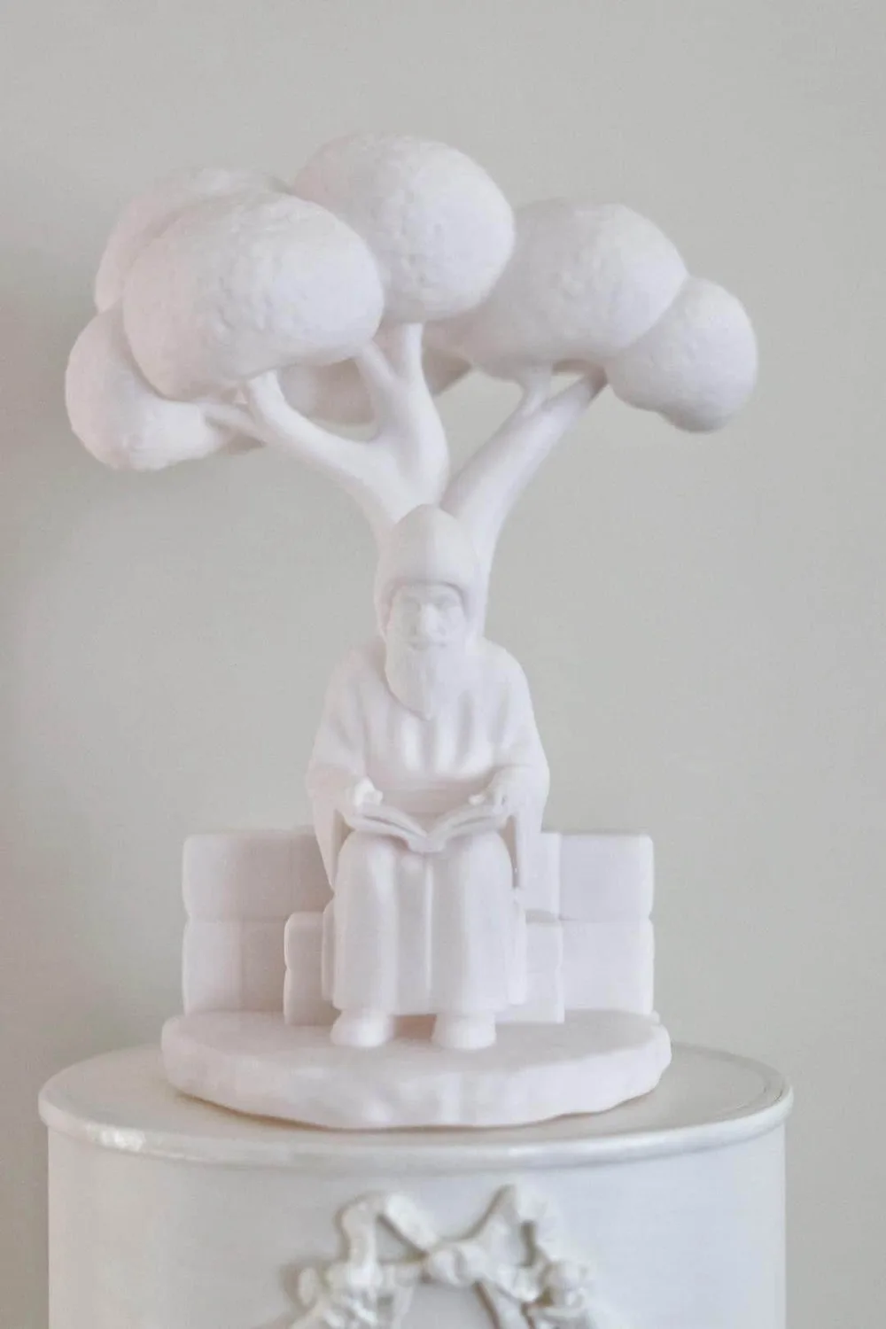 Saint Charbel seated under a tree, reading an open book