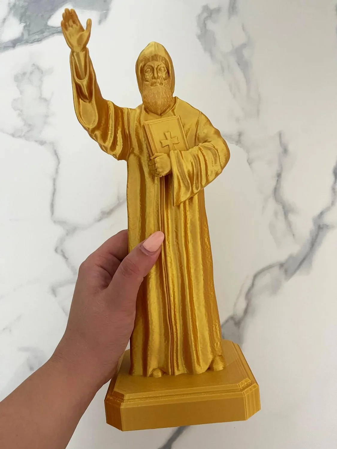 Saint Charbel statue in white, standing with hands clasped