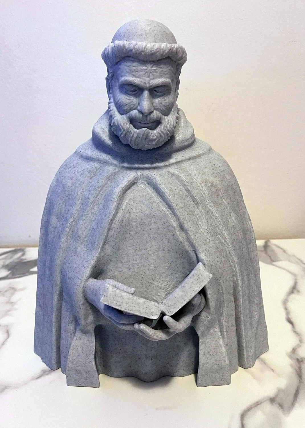 Saint Dominic de Guzmán statue in white, holding a book and lily