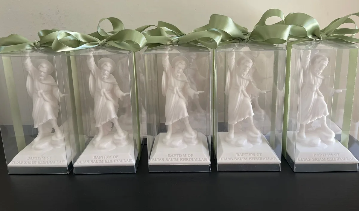 A batch of white sculptural favours in clear boxes with pale green ribbon