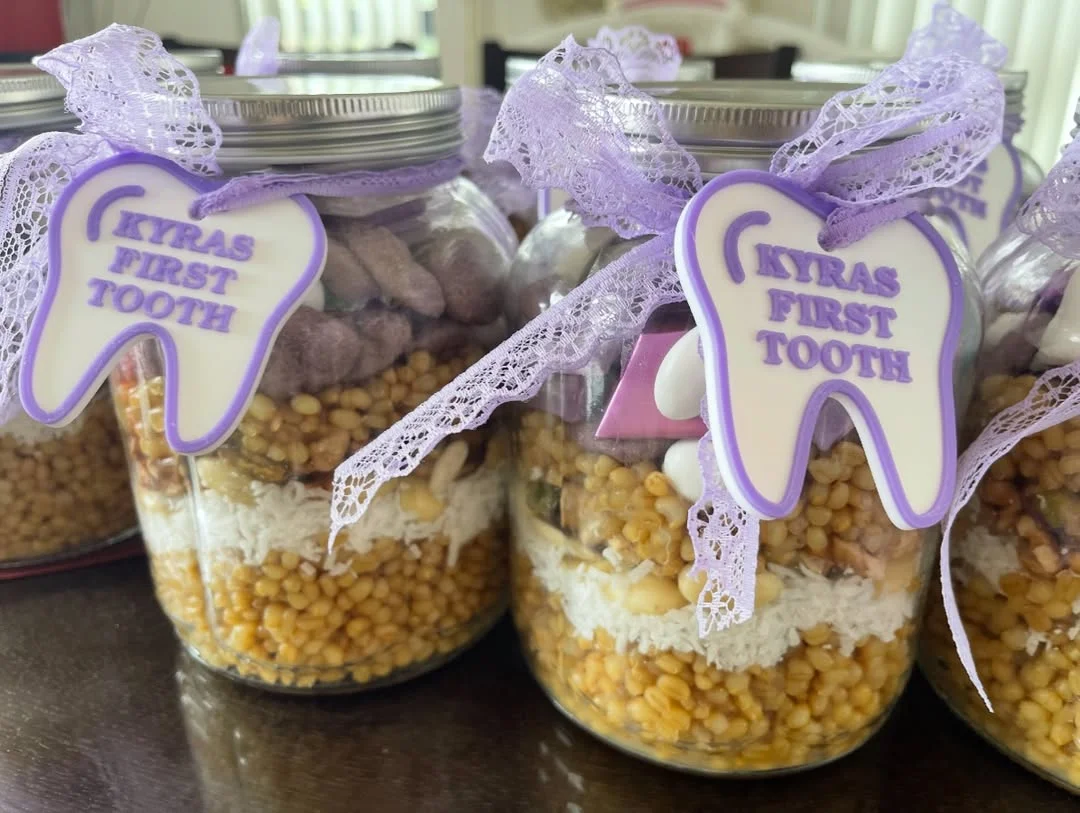 Tooth-shaped purple and white personalised tags tied to favour jars with lilac ribbon